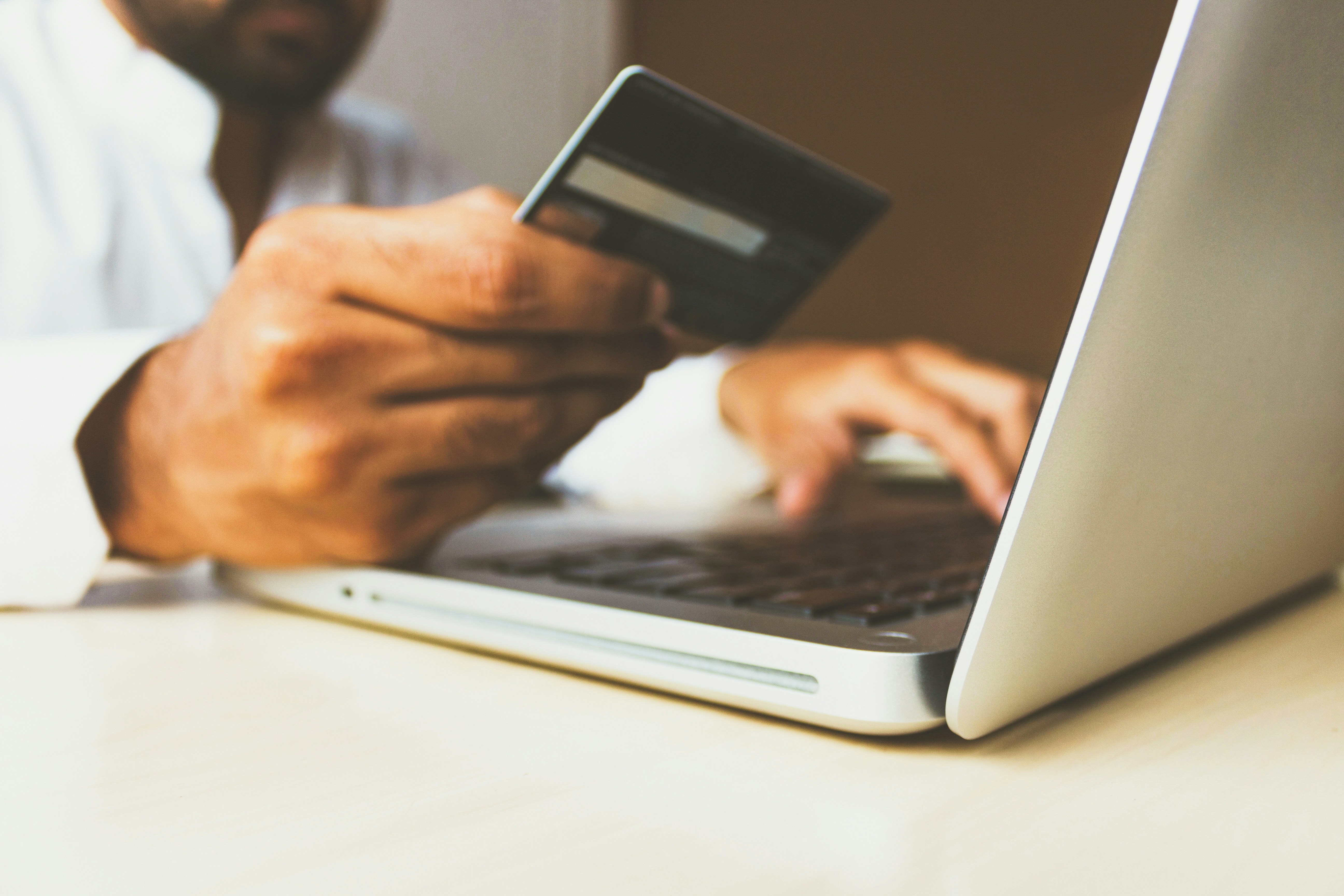 man sitting at a laptop with a debit or credit card