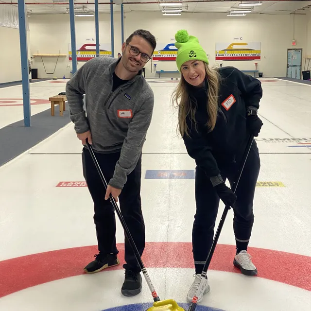 Jeff and Mo on the ice with brooms and a curling stone