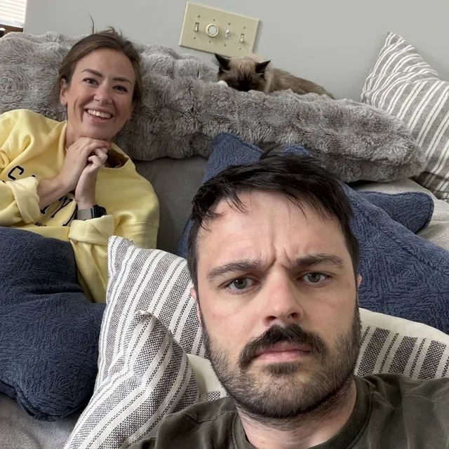 Jeff on the couch with Mo and one of the cats behind him