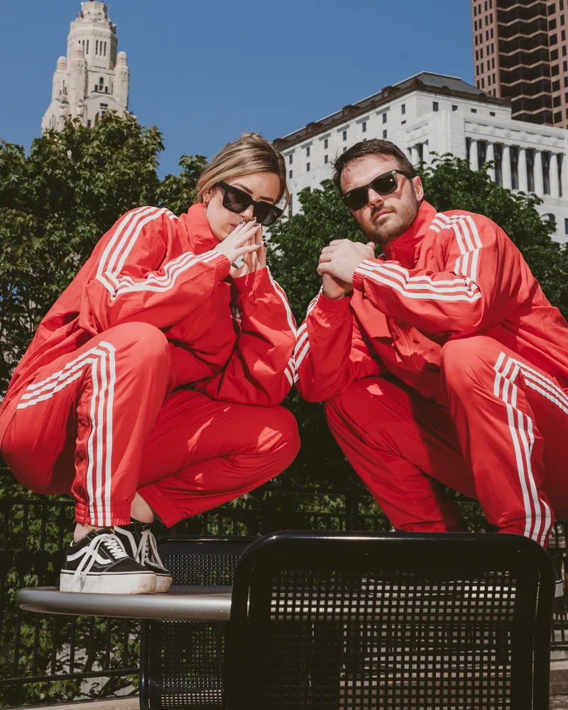 Jeff and Mo in matching red tracksuits on a bench in downtown Columbus