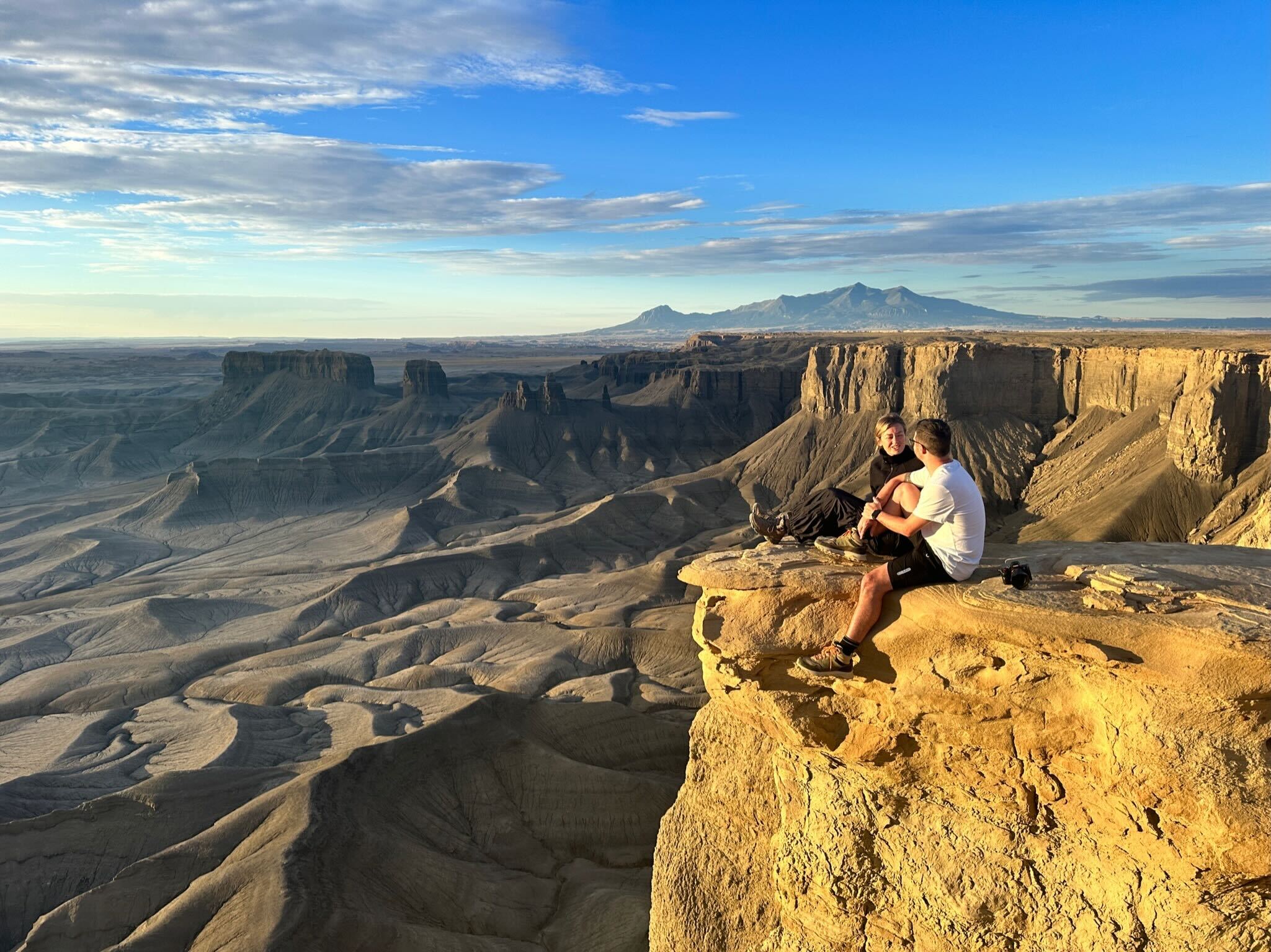 Two people sitting on a cliff in Utah